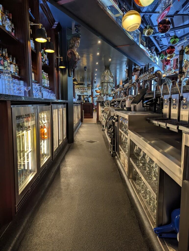 Behind the Bar at the Ship Greenwich, the colourful lights and lamps in the background and a marble head carving.