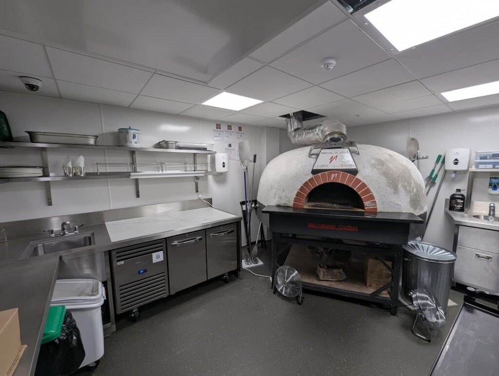 Pizza area in the kitchen with a stone pizza oven alongside a sink and a prep area.
